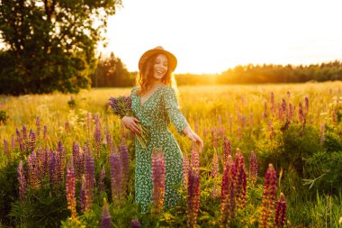Güzel bir kadın çiçek kokulu lavanta tarlalarında duruyor. Doğa, tatil, rahatlama ve yaşam tarzı. Şifalı bitkilerin toplanması
