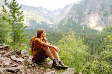Sırt çantalı yürüyüş yapan genç bir kadın. Doğa yürüyüşü. Güneşli bir manzara. Genç bir gezgin dağ patikaları boyunca seyahat eder. Macera, seyahat konsepti.