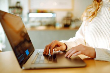 Dizüstü bilgisayarda klavye üzerinde çalışan ellerin yakın çekimi. Ev işi ve rahat bir atmosferde gezinme konsepti. Serbest, çevrimiçi kurs. İnternetten alışveriş. Siber güvenlik kavramı