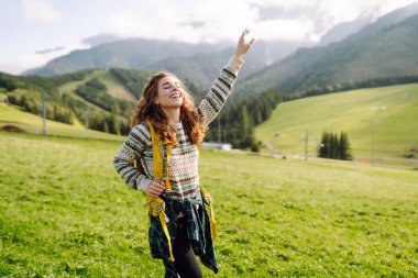 Arka plandaki yeşil çimen vadisinde yürüyen genç bir kadın. Arka plan vadisindeki turist gezgini. Yürüyüşçü dinleniyor.