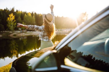 Kadın. Turist, arabası ve neşe kaynağı ile ayakta duruyor. Aktif yaşam tarzı, seyahat.
