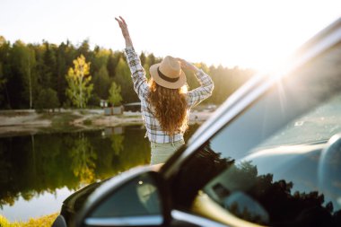 Kadın. Turist, arabası ve neşe kaynağı ile ayakta duruyor. Aktif yaşam tarzı, seyahat.