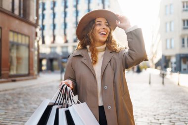 Alışveriş yapan kadın. Alışveriş merkezinin yakınında alışveriş torbaları olan genç bir turist. Bahar stili. Tüketim, satın alma, alışveriş, yaşam tarzı, satış kavramı.