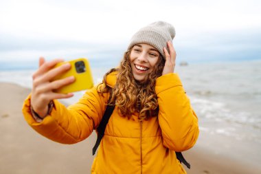 Genç bir kadın sahilde selfie çekiyor. Seyahat, yaşam tarzı, macera. Günlük tutma.