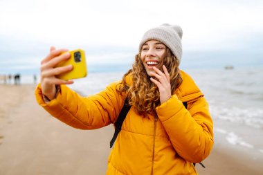 Genç bir kadın sahilde selfie çekiyor. Seyahat, yaşam tarzı, macera. Günlük tutma.