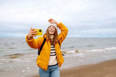 Genç bir kadın sahilde selfie çekiyor. Seyahat, yaşam tarzı, macera. Günlük tutma.