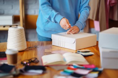 Giyim mağazası: genç kadın blogcu, küçük işletme sahibi, tablet çekleri kullanan satıcı ve çevrimiçi mağaza siparişleri, e-ticaret paketi. Çevrimiçi Alışveriş Arabası kavramı.
