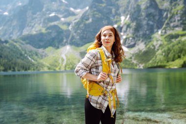 Ormanlık arka planda, göl kenarında sırt çantalı mutlu bir kadın. Yürüyüş. Doğa. Seyahat ve turizm.