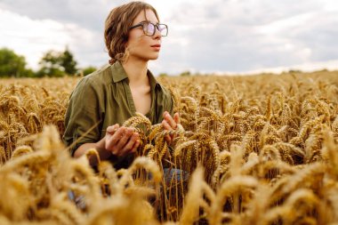 Tahıl tarlasında çalışan ve hasat geliri planlayan bir kadın tarım uzmanı. Kadın, buğday hasadının kalite kontrolünü inceliyor ve kontrol ediyor. Tarım, bahçıvanlık veya ekoloji kavramı.