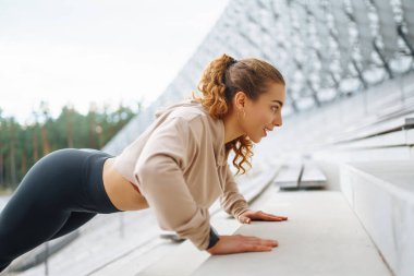 Sporcu kadın dışarıda antrenman yapıyor, esneme hareketleri yapıyor. Spor, aktif yaşam, spor eğitimi, sağlıklı yaşam tarzı..