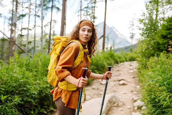 Happy backpacker woman hiking, camping through mountain forest. Adventure, travel, sport, active life.