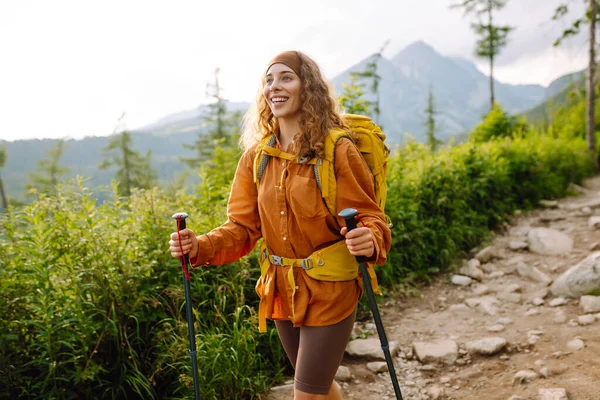 Happy backpacker woman hiking, camping through mountain forest. Adventure, travel, sport, active life.