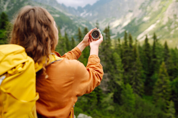 Woman holding a navigational compass on background of the mountains. The concept of hiking, nature.