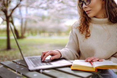 Genç bir kadın açık havada çalışıyor ve lanet parkın güzel havasının tadını çıkarıyor. Bağımsızlık, teknoloji, eğitim, iş dünyası, blog konsepti.