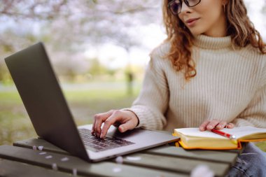 Genç bir kadın açık havada çalışıyor ve lanet parkın güzel havasının tadını çıkarıyor. Bağımsızlık, teknoloji, eğitim, iş dünyası, blog konsepti.