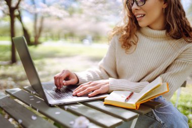 Açık havada kahve fincanı okuyan genç bir kadın. İş, blog yazma, serbest çalışma, eğitim kavramı. Dinlenme, rahatlama, rahatlama kavramı.