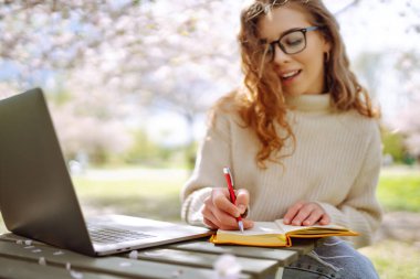 Açık havada kahve fincanı okuyan genç bir kadın. İş, blog yazma, serbest çalışma, eğitim kavramı. Dinlenme, rahatlama, rahatlama kavramı.