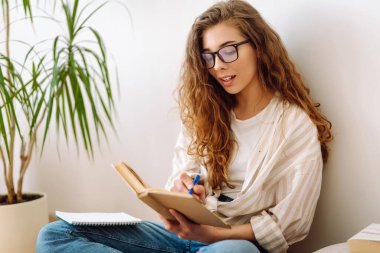 Evde ilginç kitaplar okuyan genç bir kadın. İş, blog yazma, serbest çalışma, eğitim kavramı. 