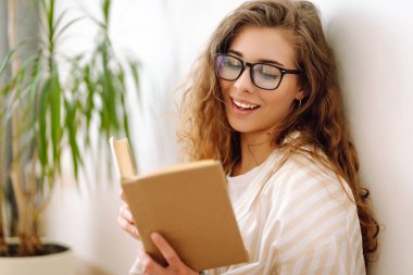 Evde ilginç kitaplar okuyan genç bir kadın. İş, blog yazma, serbest çalışma, eğitim kavramı. 