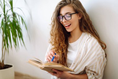 Evde ilginç kitaplar okuyan genç bir kadın. İş, blog yazma, serbest çalışma, eğitim kavramı. 