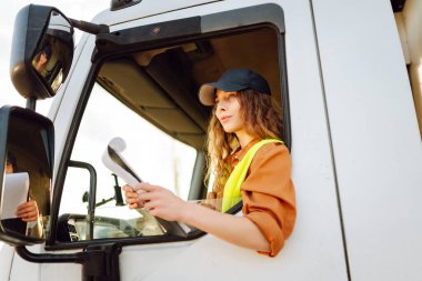 Genç bir kadın kargo kamyonunda oturuyor. Ulaştırma sektörü teması.