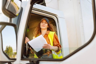 Genç bir kadın kargo kamyonunda oturuyor. Ulaştırma sektörü teması.