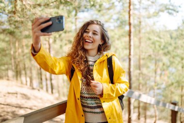 Neşeli bayan gezgin elinde akıllı telefon cihazıyla çevrede dolaşırken tatilde yeni maceranın tadını çıkaran mutlu bir kadın. Seyahat ve teknoloji