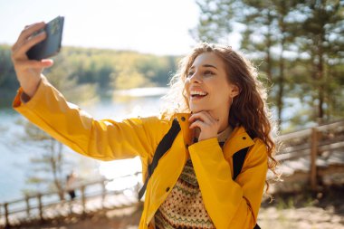 Neşeli bayan gezgin elinde akıllı telefon cihazıyla çevrede dolaşırken tatilde yeni maceranın tadını çıkaran mutlu bir kadın. Seyahat ve teknoloji