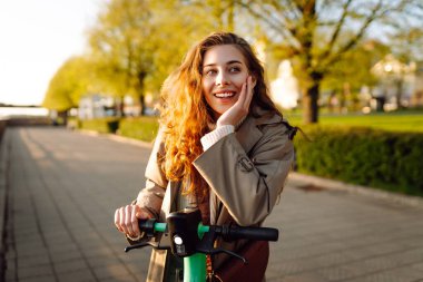 Şehirde elektrikli scooter kullanan mutlu bir kadın. Aktif hayat. Ekolojik ulaşım konsepti. Seyahat, turizm konsepti.