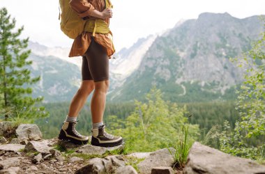 Yürüyüş yolunda duran ve manzaraya bakan yürüyüşçü bacakları. Doğa kavramı..