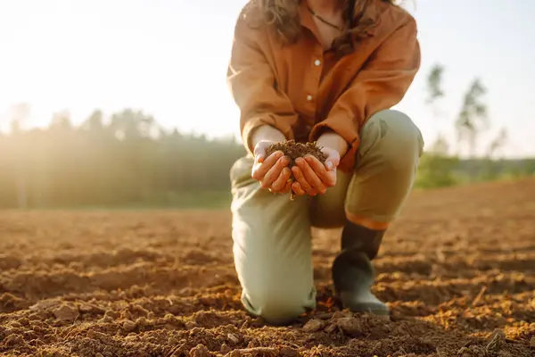 Farmer holding soil in hands close-up. Organic gardening, agriculture. Cultivated dirt, earth, ground, brown land background, nature.