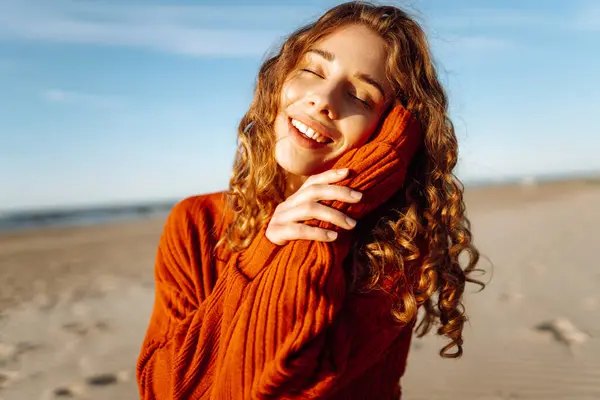 Portrait of a beautiful curly woman on the beach in cold sunny weather. Spring time.Travel, weekend, relax and lifestyle concept.