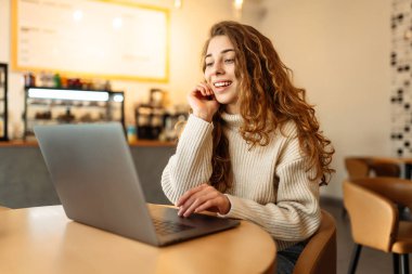 Kafede dizüstü bilgisayar kullanan güzel bir kadın. Eğitim, iş, serbest meslek kavramı. İnternetten alışveriş.