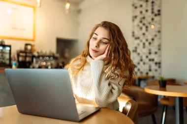 Kafede dizüstü bilgisayar kullanan güzel bir kadın. Eğitim, iş, serbest meslek kavramı. İnternetten alışveriş.