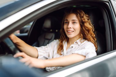 Kadın şoför. Arabada oturan süveterli güzel bir kadının portresi. Araba yolculuğu, turizm, taşıma konsepti.