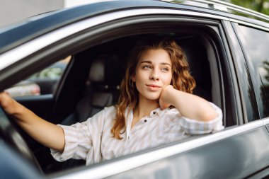 Kadın şoför. Arabada oturan süveterli güzel bir kadının portresi. Araba yolculuğu, turizm, taşıma konsepti.