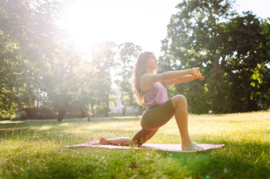 Park 'ta yoga yapan genç bir kadının portresi. Spor, aktif yaşam, sağlıklı yaşam tarzı.