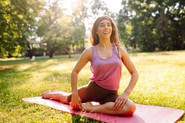 Park 'ta yoga yapan genç bir kadının portresi. Spor, aktif yaşam, sağlıklı yaşam tarzı.