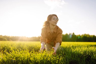 Modern tabletli bir kadın çiftçi filizleri eliyle değerlendirir, tarladaki yeşil filizleri. Tarım, bahçıvanlık veya ekoloji kavramı.
