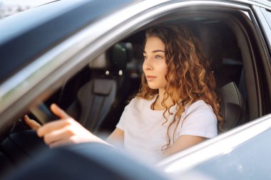 Kadın şoför. Genç bir kadının portresi araba sürüyor ve gülümsüyor. Otomobil yolculuğu.