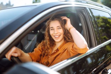 Kadın şoför. Genç bir kadının portresi araba sürüyor ve gülümsüyor. Otomobil yolculuğu.