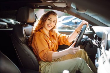 Kadın şoför. Genç bir kadının portresi araba sürüyor ve gülümsüyor. Otomobil yolculuğu.