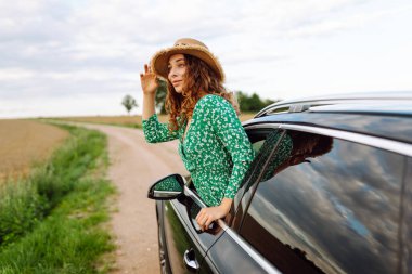Genç bir kadın araba yolculuğunun tadını çıkarıyor. Yaz tatili, tatiller, seyahat, yol gezisi ve insan konsepti - doğadaki genç kadın..