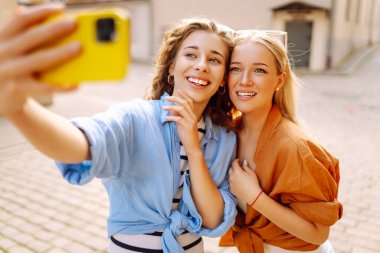 Genç arkadaşlar eğleniyor ve telefonda selfie çekiyorlar. Yaşam tarzı, eğlence, eğlence, gençlik kavramı.