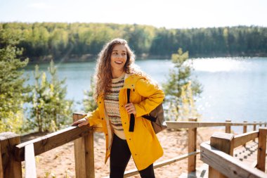 Sonbahar mevsiminde ormanda sırt çantası taşıyan mutlu bir kadın. Gezgin doğanın tadını çıkarıyor. Temiz hava. Turizm, seyahat, yürüyüş kavramı.