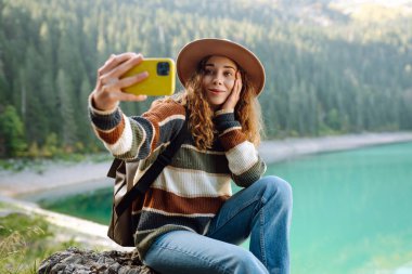 Seyahat ederken selfie. Genç bir kadınla manzara, yeşil tepeler ve göl. Yaşam tarzı, macera, doğa, aktif yaşam.