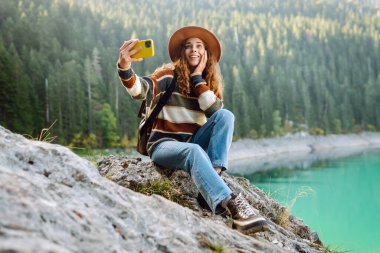 Seyahat ederken selfie. Genç bir kadınla manzara, yeşil tepeler ve göl. Yaşam tarzı, macera, doğa, aktif yaşam.