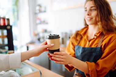 Bayan barista müşteriye emir veriyor, karton bardakta kahve. Paket yemek konsepti.