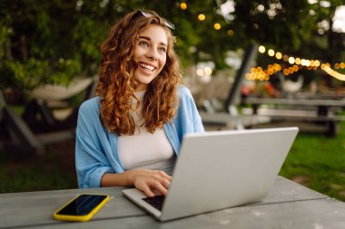 Dışarıda çalışan genç bir kadın güzel havanın tadını çıkarıyor. Bağımsızlık, teknoloji, eğitim, iş dünyası, blog konsepti.