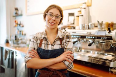 Önlüklü genç bayan kafe sahibi kameraya bakıp gülümsüyor. İş konsepti. Yiyecek ve içecek konsepti.